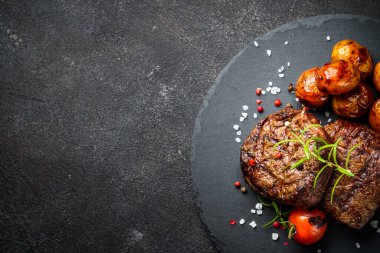 Barbekü yemeği. Sebzeli et biftekleri ve siyah arka planda otlar. Kopyalama alanı olan en üst görüntü.