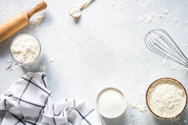 Flour, sugar, eggs and rolling pin at light stone table. Top view with copy space.