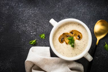 Koyu taş masada mantar çorbası. Sıcak vejetaryen yemeği, kremalı çorba. Bitki bazlı gıda.