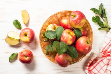Elmalar. Beyaz ahşap masadaki sepetin içinde taze kırmızı elmalar. Üst görünüm.