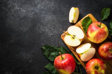 Taze olgun elmalar, siyah taş masada bütün ve dilimlenmiş elmalar. Kopyalama alanı olan üst görünüm.