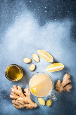 Limonlu sıcak zencefil çayı ve malzemeli cam bardakta bal. Gri taş masadaki üst görünüm.