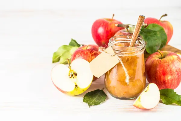Apple jam with spices and fresh apples on white background.