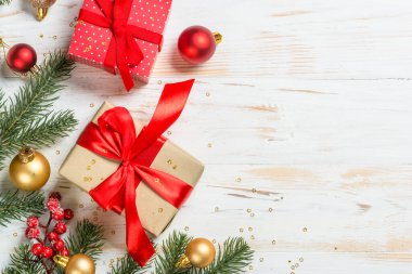 Kırmızı kurdeleli ve Noel süslemeli Noel hediyesi kutusu. Kopya alanı olan beyaz ahşap masadaki üst görünüm.
