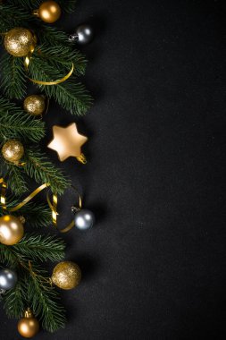 Köknar ağacı ve altın süslemeleri olan siyah noel arkaplanı. Kopyalama alanı olan düz resim.