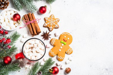 Noel yemeği. Marşmelovlu sıcak çikolata ve beyaz masada tatil süslemeleri olan zencefilli kurabiye. Kopyalama alanı olan üst görünüm.