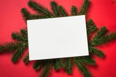 Noel arkaplanı köknar ağacı ve kırmızı arka planda süslemelerle yatıyordu. Mesajın için boşluğu olan Noel tebrik kartı.