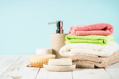 Beyaz masada seramik sabun, şampuan ve havlu ile banyo kompozisyonu. Çevre dostu banyo aksesuarları, sıfır atık konsepti.
