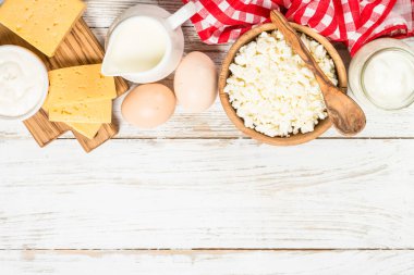 Süt ürünleri beyaz tahta masada. Krema, süt, yoğurt, peynir ve yumurta. Organik çiftçi yemeği. Kopyalama alanı olan üst görünüm.