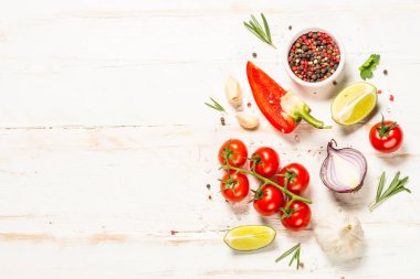 Beyaz ahşap masada yemek pişirme geçmişi. Taze sebzeler, baharatlar, otlar ve yağ. Yemek yapmak için gerekli malzemeler. Kopyalama alanı olan üst görünüm.