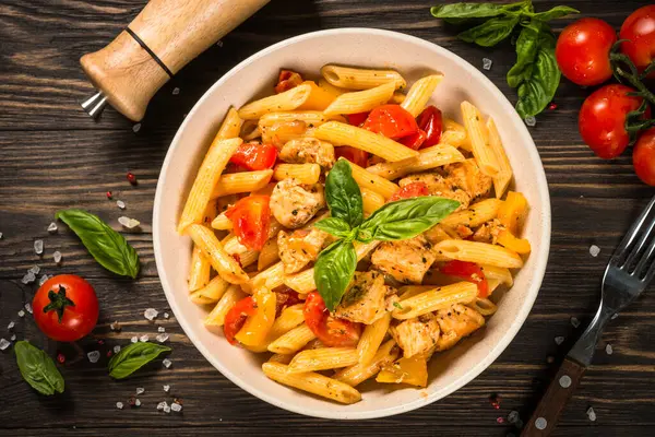 Tahta masada tavuk ve sebzeli makarna. Geleneksel İtalyan yemekleri. Üst görünüm.