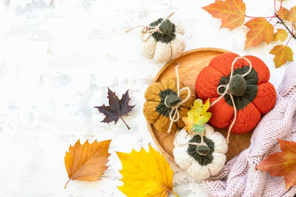 Autumn table decorations. Craft knitted pumpkins on white. Flat lay. Autumn cozy decorations.