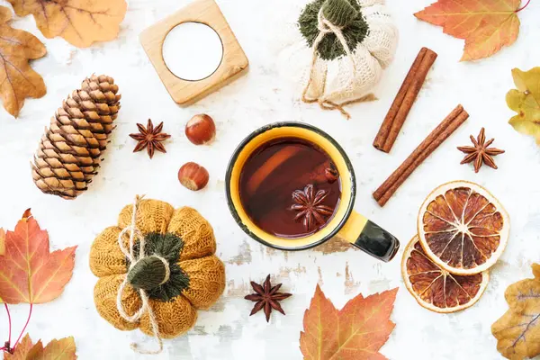 Fall background. Cozy autumn on white. Cup of spicy tea, autumn leaves, spices and decor. Flat lay with copy space.