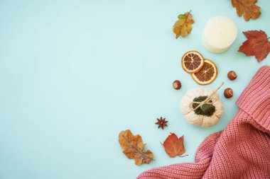 Sonbahar arkaplanı mavi. Sıcak örülü süveter, kuru yapraklar ve dekorasyonlar. Düz görünüm.