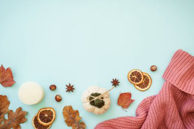 Sonbahar arkaplanı mavi. Sıcak örülü süveter, kuru yapraklar ve dekorasyonlar. Düz görünüm.