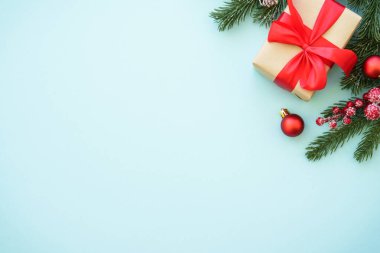 Noel hediyesi kutusu ve mavi arka planda kırmızı süslemeler. Kopyalama alanı olan düz resim.