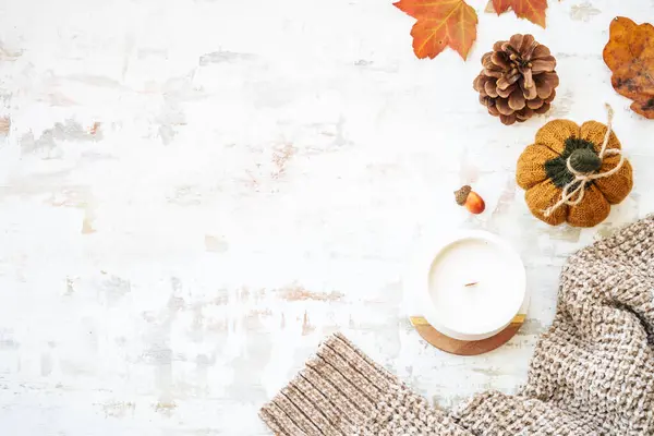 Cozy autumn background on white. Warm sweater, autumn leaves, candle and decor. Flat lay image with copy space.