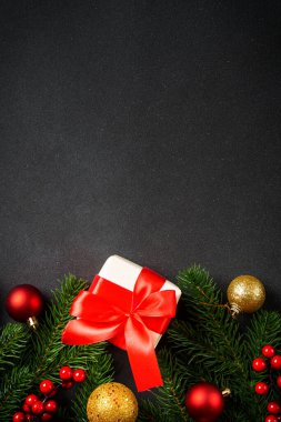 Noel arkaplanı, Noel ağacı, hediye kutusu ve siyahta tatil süslemeleri. Kopyalama alanı ile dikey resim yatıyordu.