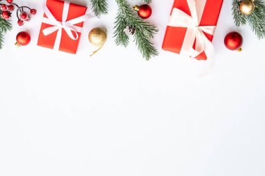 Noel hediyesi kutusu ve beyaz arka planda kırmızı süslemeler. Kopyalama alanı olan düz.