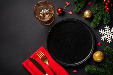 Noel yemeği. Siyah tabak, şarap kadehi, çatal bıçak takımı ve bayram süslemeleriyle Noel sofrası. Metin için boşluk ile düz uzandı.