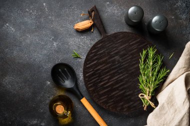 Mutfak masası. Baharat ve bitkiler, siyah arka planda kesim tahtası. Kopyalama alanı olan üst görünüm.