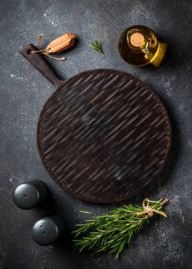 Mutfak masası. Baharat ve bitkiler, siyah arka planda kesim tahtası. Kopyalama alanı olan üst görünüm.