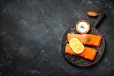 Siyah masada çiğ balık. Limon ve baharatlı somon filetosu. Kopyalama alanı olan üst görünüm.