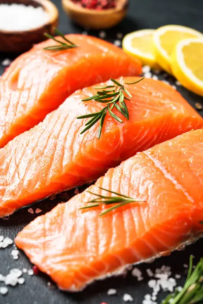 Somon fileto, biberiyeli taze balık ve siyah arka planda baharatlar..