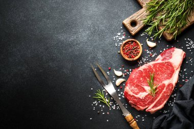 Siyah arka planda baharatlı biftek. Pirzola, çiğ et. Kopyalama alanı olan üst görünüm.