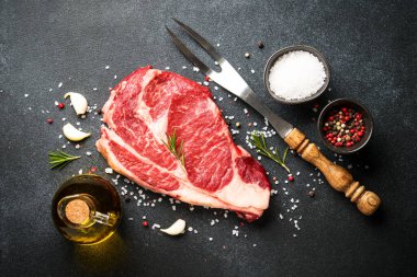 Siyah arka planda baharatlı biftek. Pirzola, çiğ et. Kopyalama alanı olan üst görünüm.