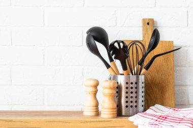 Kitchen utensils. Cooking tools with wooden cutting boards, oil and shaker at white modern kitchen interior.
