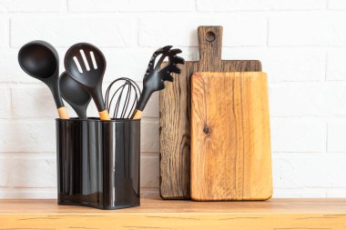 Kitchen utensils. Cooking tools with wooden cutting boards, oil and shaker at white modern kitchen interior.