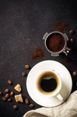 Coffee cup and coffee beans at dark table . Top view image with copy space.