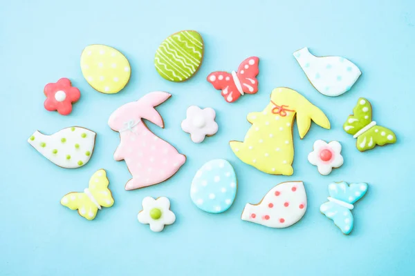 Easter gingerbread cookies on blue, Colored eggs, rabbit, flowers and others. Flat lay with copy space.