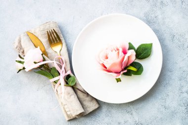 Masa seti, beyaz tabakla servis edilen şenlik masası, modern çatal bıçak takımı ve pembe çiçekler. Kopyalama alanı olan beyaz görünüm.