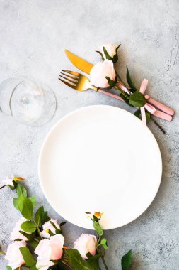 Beyaz tabak, çatal bıçak takımı ve pembe çiçekli şarap kadehi. Bahar masası seti. Kopyalama alanı olan düz.