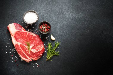 Biftek. Biftek kuru ve siyah arka planda baharatlar var. Üst görünüm.