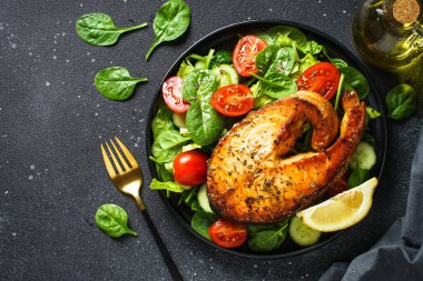 Somon bifteği ve siyah arka planda taze yeşil salata. Keto diyeti, sağlıklı yiyecekler. Üst görünüm kopyalama alanı.
