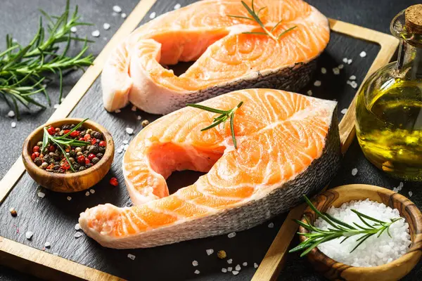 Siyah arka planda kesme tahtasında taze somon balığı bifteği. Makro.