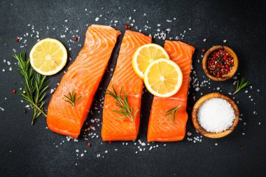 Siyah masada çiğ balık. Limon ve baharatlı somon filetosu. Kopyalama alanı olan üst görünüm.