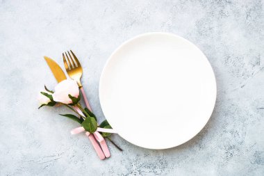 Masa seti, beyaz tabakla servis edilen şenlik masası, modern çatal bıçak takımı ve pembe çiçekler. Kopyalama alanı olan beyaz görünüm.