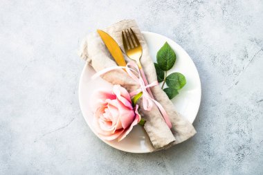 Masa düzenleme, beyaz tabak, çatal bıçak ve çiçeklerle servis edilen şenlik masası. Üst görünüm beyaz.