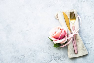 Çatal bıçak takımı ve gül çiçekleri. Kopya alanı ile beyaz arkaplanda düz uzandı.