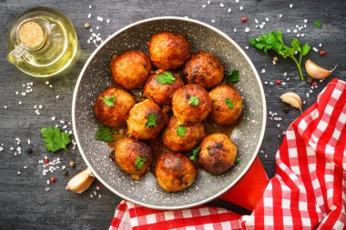 Karanlık masadaki tavada domates soslu köfte. Düz görünüm.