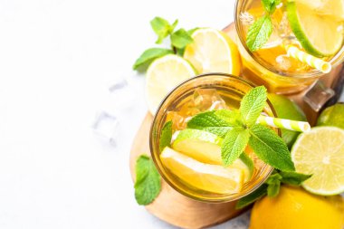 Limonlu buzlu çay, limon, nane ve buz. Soğuk limonata, yaz içkisi, beyaz arka plan. Kopyalama alanı olan üst görünüm.