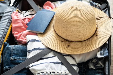 Yaz giysisi, şapka ve pasaportlu bavulu aç.