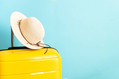 Yaz tatili, seyahat konsepti. Bavul, şapka ve parmak arası terlikler mavi arka planda.