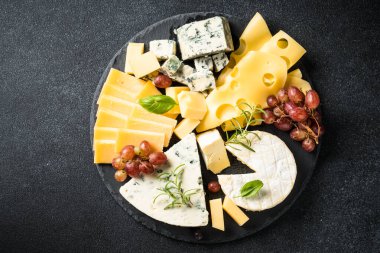 Peynir çeşnili peynir tabağı ve siyah arka planda üzüm. Kopyalama alanı olan üst görünüm.