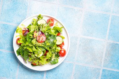 Beyaz tabakta taze yapraklı yeşil sebze salatası. Sağlıklı yemekler, diyet menüsü. Metin için boşluk olan üst görünüm.