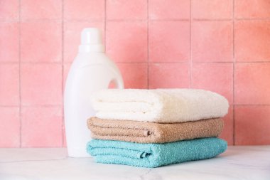 Çamaşırhanede ya da banyoda fayans duvarına karşı temiz havlular ve jel deterjanlar..